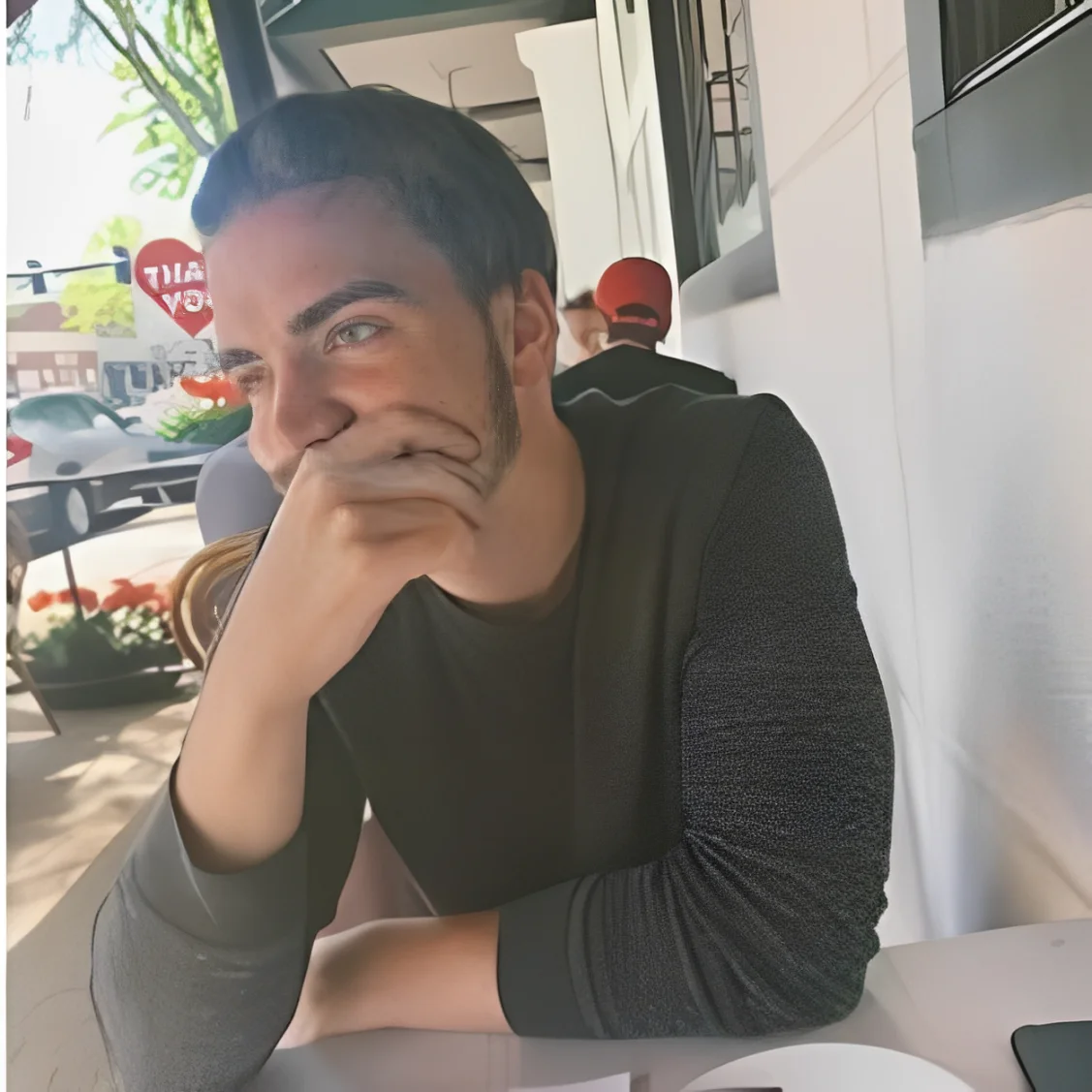 Young man smiling at outdoor cafe table