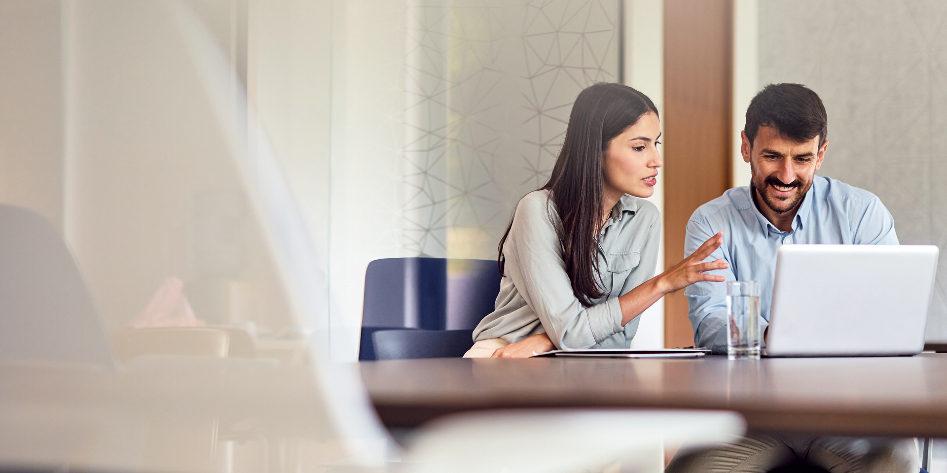 Colleagues discussing work at a laptop